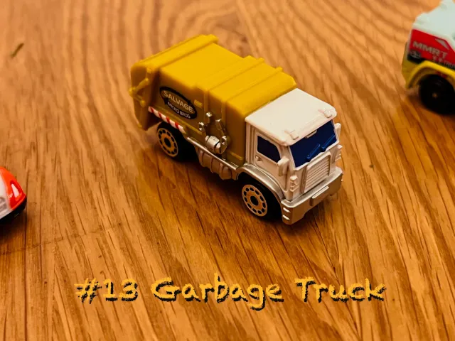 A carousel photo displaying the thirteenth vehicle named 'Garbage Truck' out of an array of 'Large Vehicles', at full size. The truck is painted yellow all sides except front painted white. With the following title 'Salvage Micro Bros' printed on the right side base cover.