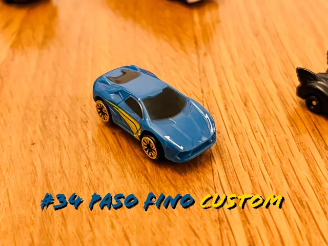 A carousel photo displaying the thirty-fourth vehicle named 'Paso Fino Custom' out of an array of 'Deluxe Cars', at full size. The car is mostly painted ocean-blue, with two strikes of gorgeous yellow on the car's right side.