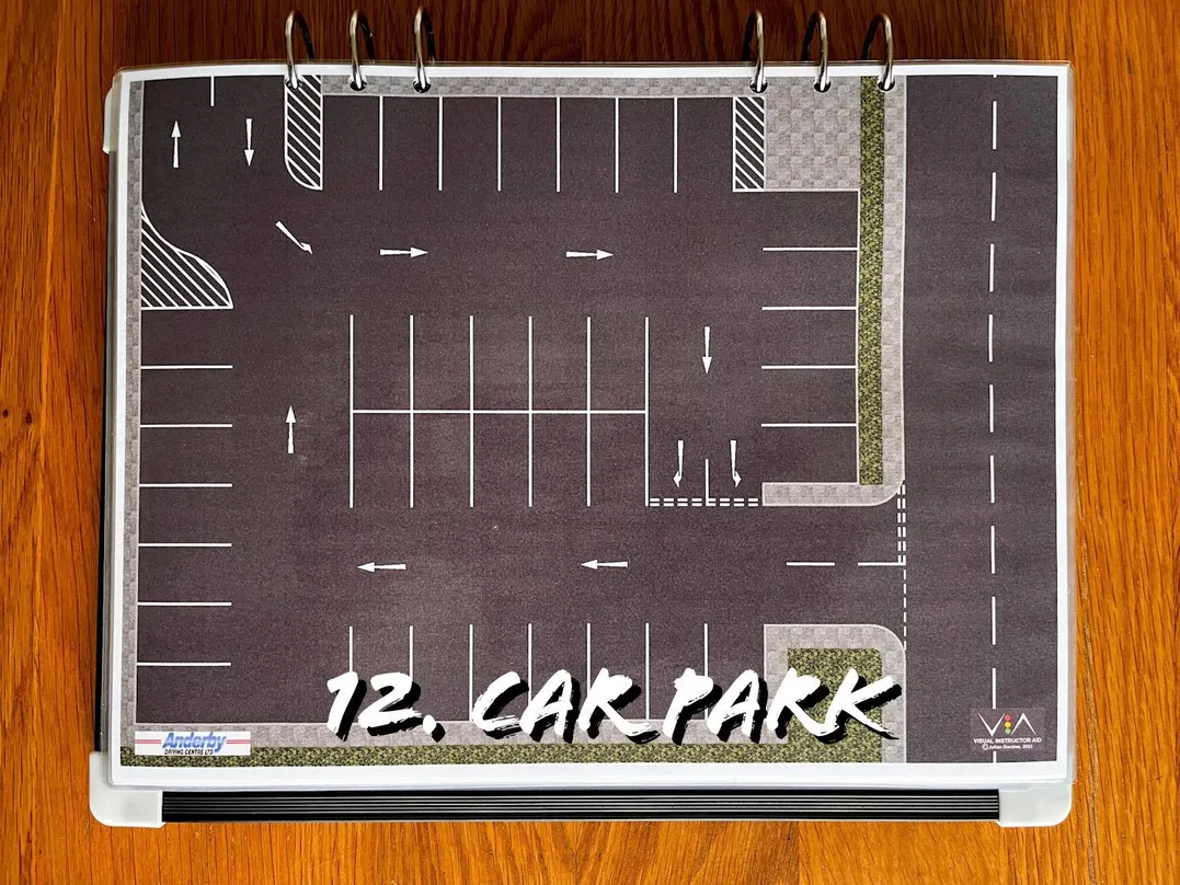 A carousel photo displaying the twelfth plan named 'car park' out of an array of roads layouts, at full size. Consisting of regular parking spaces and a one-way road surrounding the parking spots in a clockwise manner.