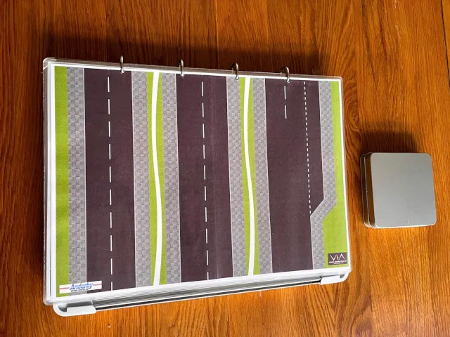 V.I.A. Kit's road layouts and metal tin on a wooden surface.