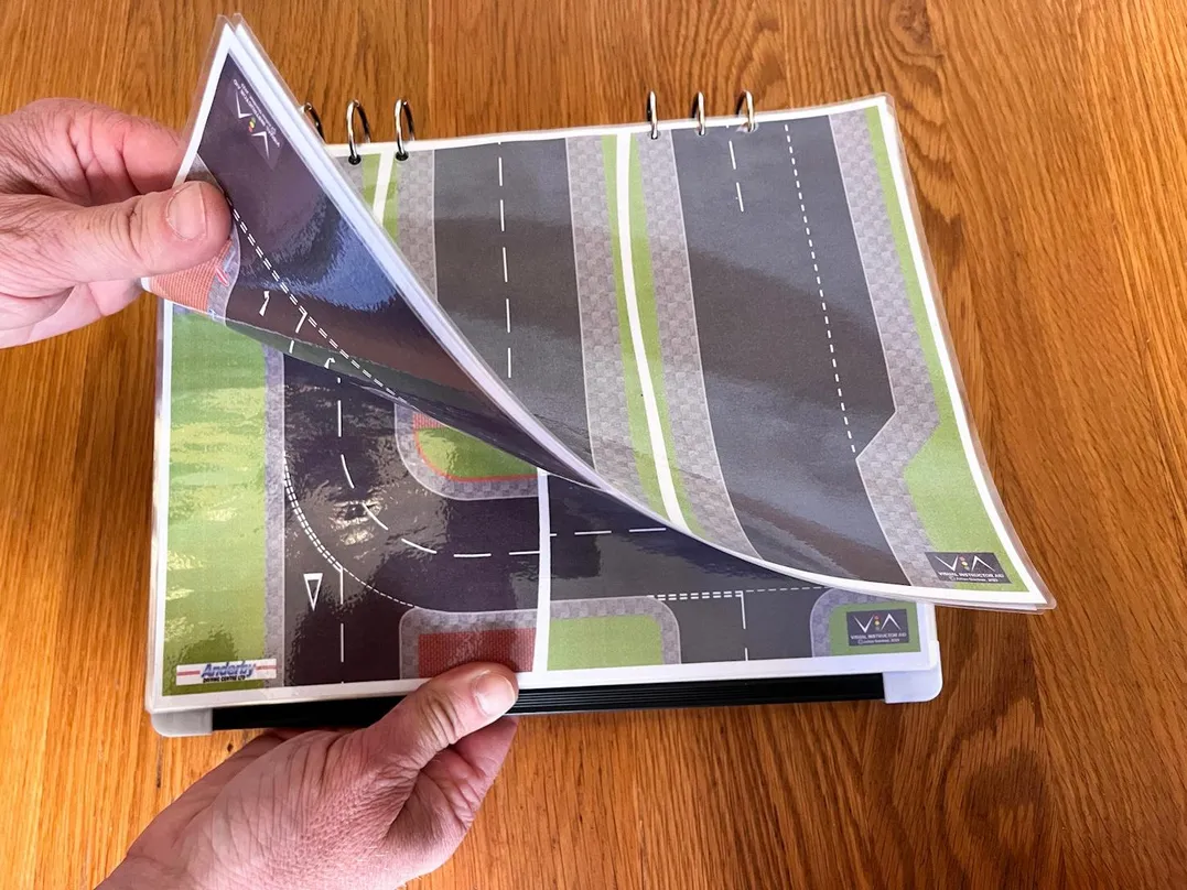 Eighth 'Compact & Convenient' carousel image with Julian's hand flicking through the mini V.I.A. road layouts like it's a book.